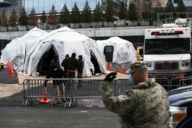  Pekerja dan anggota Pengawal Negara membina rumah mayat sementara di luar Hospital Bellevue di New York, kelmarin. Bilangan kematian di AS akibat COVID-19 melonjak melepasi 1,000, dengan 68,000 jangkitan yang disahkan. — Gambar AFP