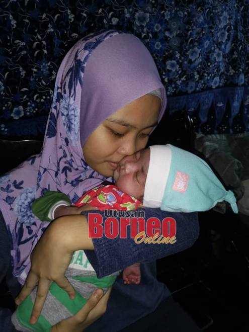 Isteri Azizul mencium bayinya yang didukungnya.