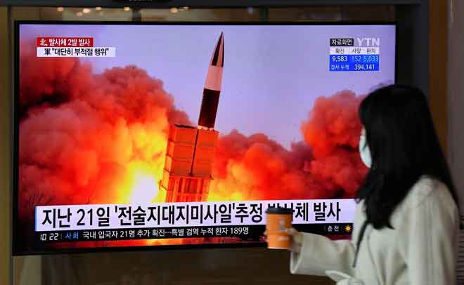  Seorang wanita melintasi skrin televisyen memaparkan rakaman fail ujian misil Korea Utara di sebuah stesen kereta api di Seoul, semalam. — Gambar AFP