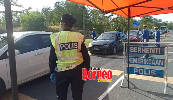  Anggota polis dan Angkatan Pertahanan Awam Malaysia sedang membuat pemeriksaan ke atas kenderaan yang lalu di Jalan Lintas Utara Sandakan.