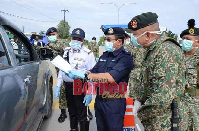  Johnny (kanan) dan Zulkipli (dua kanan) bersama anggota                                                                                             polis dan tentera memeriksa surat kebenaran bekerja yang              dikeluarkan majikan semasa tempoh PKP bagi perkhidmatan penting di Bintulu.