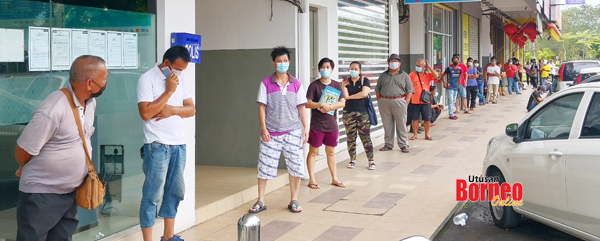  keadaan orang ramai yang berbaris menunggu giliran memasuki bank.