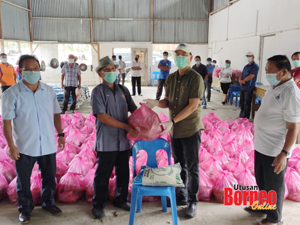  Madius menyampaikan sumbangan kepada salah seorang MPKK sambil disaksikan Joisin (kiri) dan Suali (kanan).