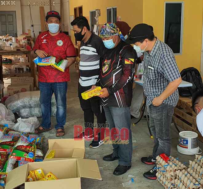  Lukanisman (kiri) menunjukkan bungkusan bantuan makanan kepada dua pegawai SPRM (di sebelah kiri beliau) di Sibuti semalam.