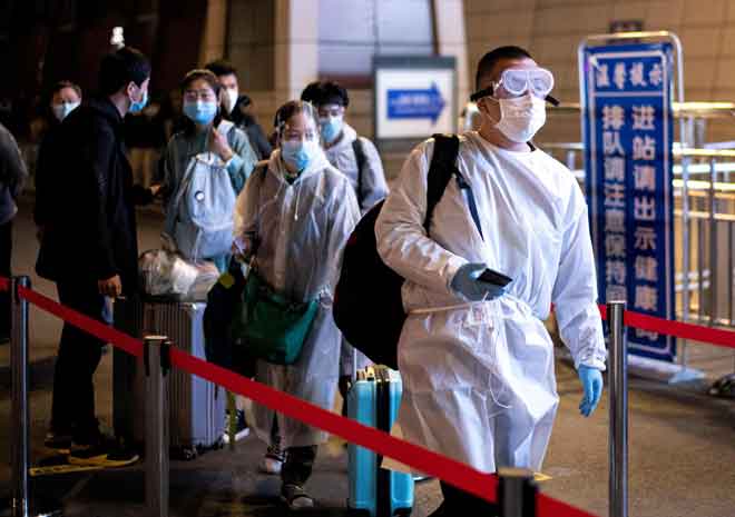  Orang ramai memakai sut hazmat tiba di Stesen Kereta api Wuhan Wuchang untuk meninggalkan Wuhan pada awal semalam selepas pihak berkuasa China menarik balik larangan perjalanan selama 76 hari ke atas kota itu. — Gambar AFP 