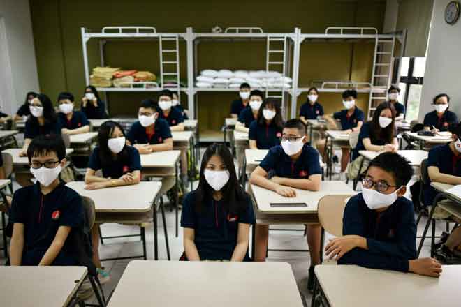  Para pelajar memakai topeng muka duduk menunggu guru di dalam bilik kelas di Sekolah Marie Curie di Hanoi, semalam. — Gambar AFP