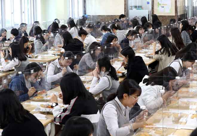  Para pelajar terpisah oleh skrin pelindung sebagai langkah pencegahan COVID-19 ketika makan tengah hari di kantin sekolah tinggi di daerah Daejeon, Korea Selatan semalam. — Gambar AFP