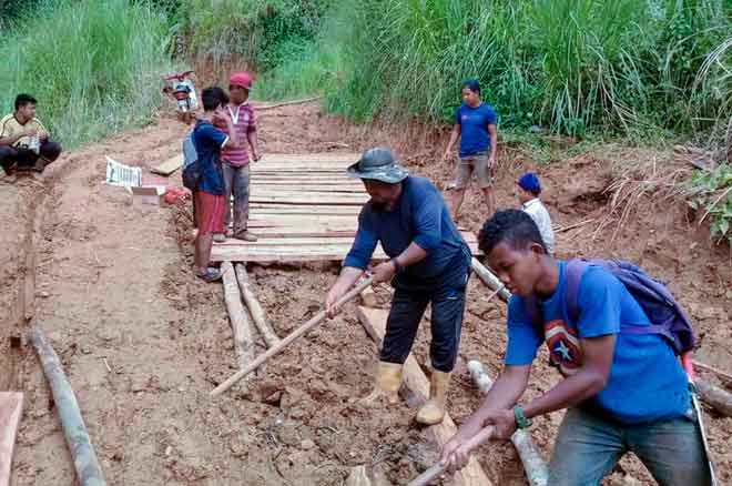  Penduduk Orang Asli kelihatan bergotong royong membina rakit kayu di Pos Bihai yang berlumpur bagi memudahkan anak-anak mereka pergi ke Sekolah Menengah Kebangsaan Tengku Indera Petra 1 (SMKTIP1) Gua Musang, semalam. — Gambar Bernama