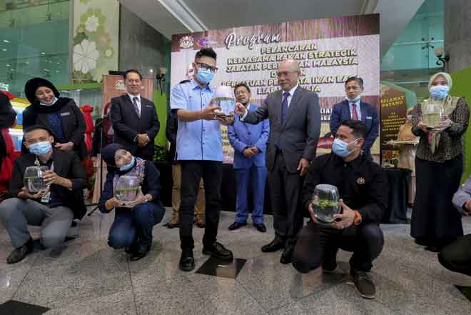  Ronald menyerahkan ikan laga kepada pengunjung, Azri pada program pelancaran kerjasama rakan strategik Jabatan Perikanan dengan Persatuan Ikan Laga Liar di Kementerian Pertanian dan Industri Makanan, Putrajaya, semalam. — Gambar Bernama