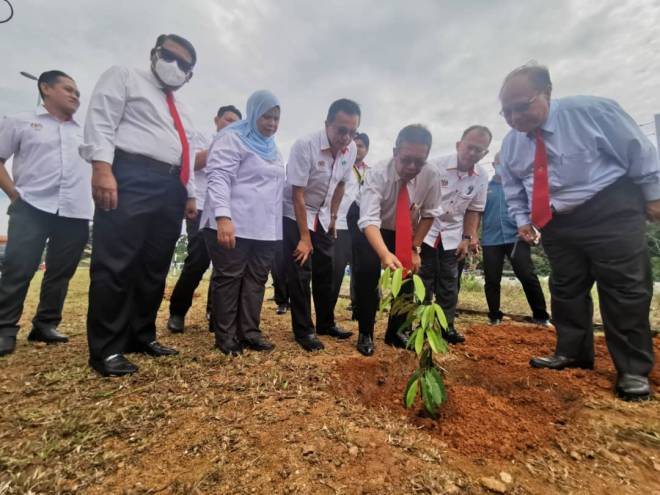 Latiff (tiga kanan) ditemani Henry (kanan), Abdullah, Rubiah dan Salem menanam pokok durian 'Musang King' sebagai gimik perasmian Pejabat Baharu RISDA Sarawak.