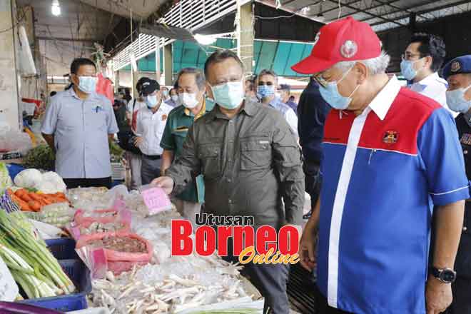  Datuk Alexander Nanta Linggi (dua kanan) menunjukkan tanda harga berwarna merah jambu kepada Menteri Pendidikan, Sains dan Penyelidikan Teknologi Dato Sri Micheal Manyin Jawong (kanan) semasa mengadakan lawatan di gerai ayam sempena Skim Harga Maksimum Musim Perayaan (SHMMP) di Pasar Serian pada 27 Mei lepas. — Gambar Chimon Upon