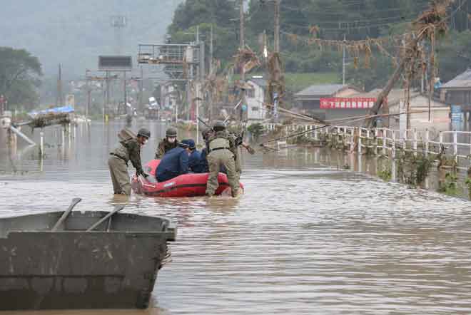  Anggota polis dan anggota tentera Japan Self-Defense Forces mengendali bot boleh kembung turut serta dalam usaha operasi menyelamat di rumah penjagaan berikutan hujan lebat di perkampungan Kuma, Kumamoto, semalam. — Gambar AFP