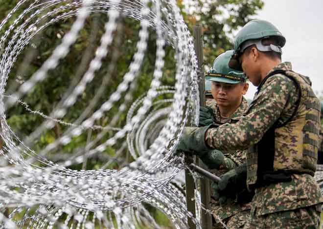  Anggota Skuadron Ke-7 Rejimen Askar Jurutera Diraja melakukan kerja-kerja pemasangan kawat duri bagi membendung kemasukan PATI dan aktiviti penyeludupan antara sempadan Malaysia-Thailand menerusi Ops Benteng COVID-19 di Pangkalan Haram Pok Nik, Jeram Perdah, dekat Pasir Mas semalam. — Gambar Bernama