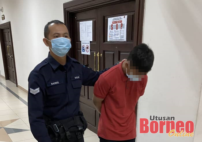 Tertuduh diiringi pegawai polis di lobi Kompleks Mahkamah Kuching, hari ini. 