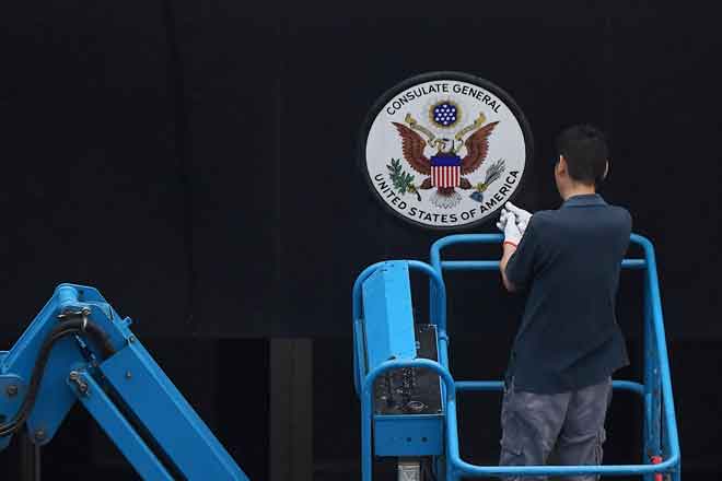  Seorang pekerja menanggalkan lambang negara AS di konsulat AS di Chengdu, wilayah Sichuan di China, semalam. — Gambar AFP