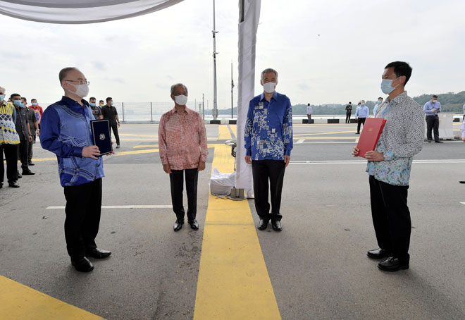  Muyhiddin bersama Lee menyaksikan Wee (depan, kiri) dan Ong (depan, kanan) memegang dokumen perjanjian di atas Tambak Johor sebagai simbolik “persetujuan” dua hala untuk meneruskan projek Sistem Transit Rapid (RTS) yang menghubungi Johor Bahru-Singapura di Johor Bahru, semalam. — Gambar Bernama