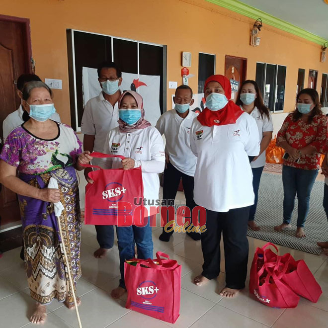  Rosey (tengah) nyuaka pemeri ari baruh SKS ngagai siku penerima seraya dikemataka Sarkawi (baris belakang dua kiba) enggau bala ke bukai.