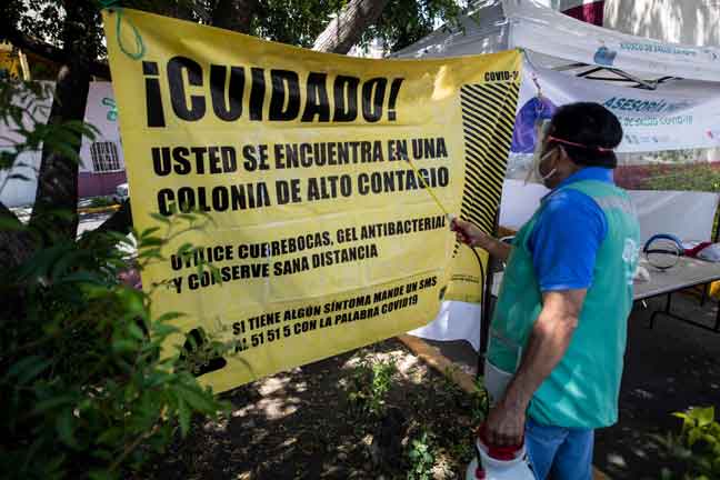  Seorang pekerja menyah cemar sepanduk di kaunter yang menyediakan saringan untuk mengesan COVID-19 di Kota Mexico kelmarin.  — Gambar AFP
