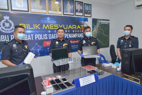  Haris menunjukkan barangan elektronik yang dirampas di calling centre di sebuah kondominium di sini.