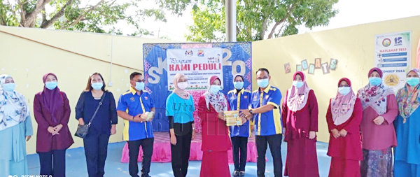  Iswadiman (lima, kanan) menyampaikan sumbangan pelitup separuh muka dan cecair pembasmi kuman kepada Guru Besar SK Merpati pada Program Kami Peduli di dewan terbuka sekolah itu.