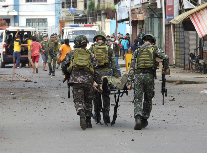  Anggota tentera mengangkat rakan mereka selepas satu bom buatan sendiri meletup di sebelah kenderaan tentera di bandar Jolo, pulau Sulu kelmarin. — Gambar AFP
