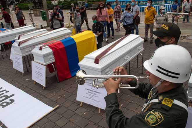  Anggota polis meniup trompet di sebelah beberapa keranda yang                     diperagakan sebagai sebahagian daripada protes terhadap keganasan di Colombia di mana beberapa pembunuhan berlaku sejak beberapa hari lalu di Medellin pada Isnin lepas. — Gambar AFP 