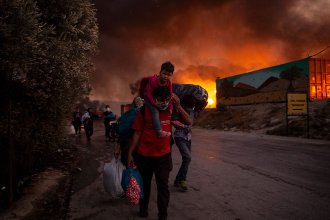  Pencari suaka bersama kanak-kanak dilihat melarikan diri dari kebakaran besar yang meletus di kem pendatang Moria di pulau Lesbos, Greece kelmarin. — Gambar AFP