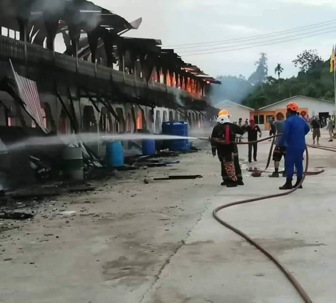 Bomba giat memadamkan kebakaran rumah panjang di Rasau, hari ini. - Gambar ihsan JBPM