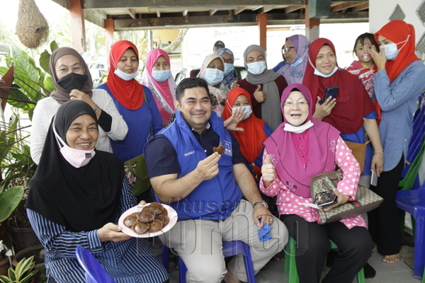  Shahelmey merasa kuih penjaram pada lawatan ziarah ke Program Memasak Panjaram di kediaman Halimah Alang Laut (duduk kiri) di Kampung Sri Pandan, Putatan.