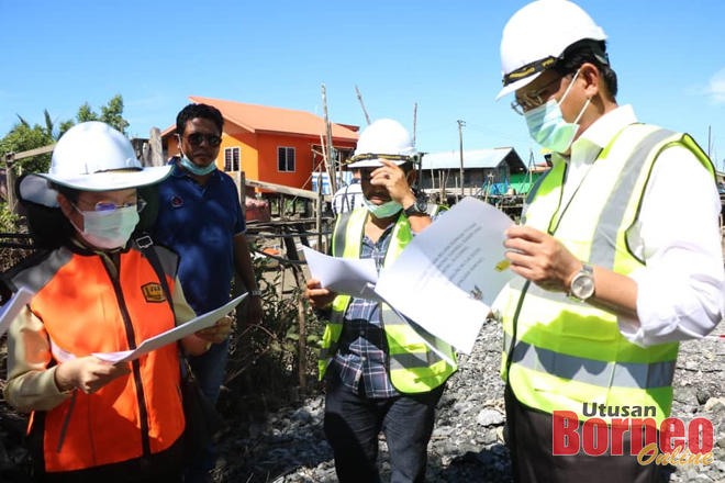 Dr Abdul Rahman (kanan) mendengar penerangan ringkas dari pegawai JKR berhubung projek di Kampung Buntal.