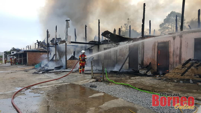 Bomba memadamkan sisa kebakaran rumah panjang, hari ini. 