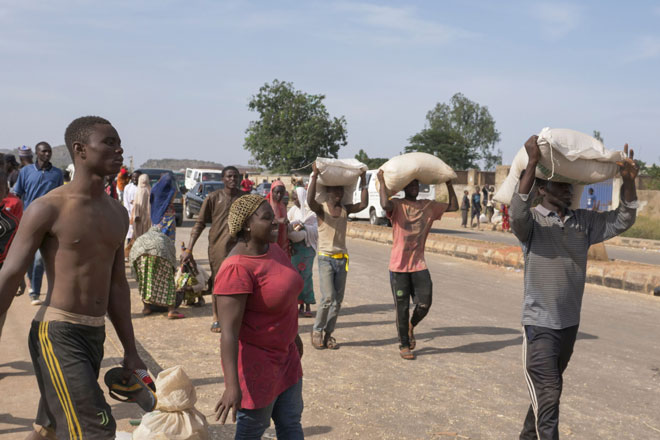  Orang ramai membawa balik barang makanan dari sebuah gudang makanan yang digeledah di Jos, Nigeria. — Gambar AFP