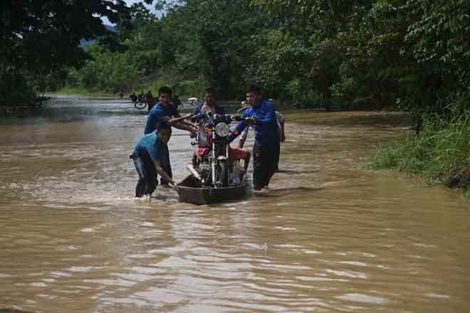  Penduduk mengangkut motosikal di atas sebuah bot di kawasan yang dilanda banjir selepas Taufan Eta melanda Panzos, Alta Verapaz, 220 kilometer utara Guatemala. — Gambar AFP