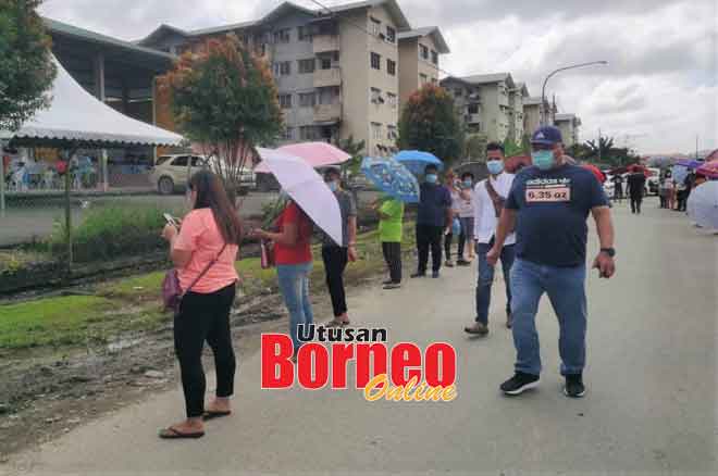  Tiong (kanan) meninjau dan memantau penduduk yang beratur menunggu giliran untuk membuat saringan ujian calitan pengesanan COVID-19 di Sungai Plan Tanjung Kidurong Bintulu, kelmarin.