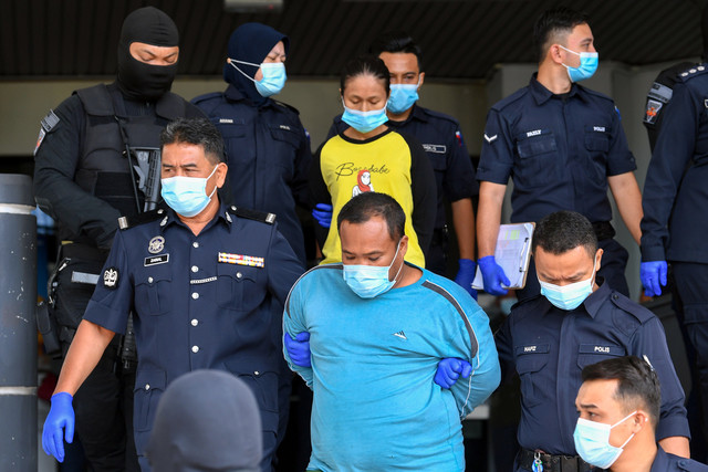 Polis melakukan kawalan ketat terhadap ibu kandung dan bapa tiri kanak-kanak lelaki yang ditemukan lemas di dalam tong air, ketika hadir bagi pertuduhan kes dera di Mahkamah Ayer Keroh hari ini. - Gambar Bernama