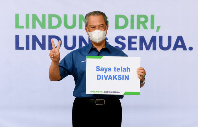 Muhyiddin memegang playkad 'Saya Telah Divaksin' selepas mengambil suntikan vaksin Pfizer-BioNTech di Pusat Kesihatan Daerah Presint 11 hari ini. - Gambar Bernama 