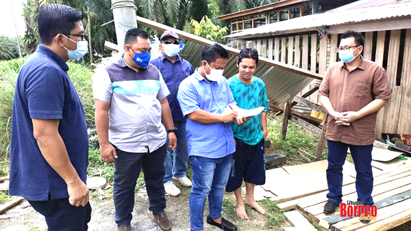  Rohaizan menulis data seorang penduduk Kg Tanjung Bulat sambil diperhatikan oleh Abu Bakar (kanan).