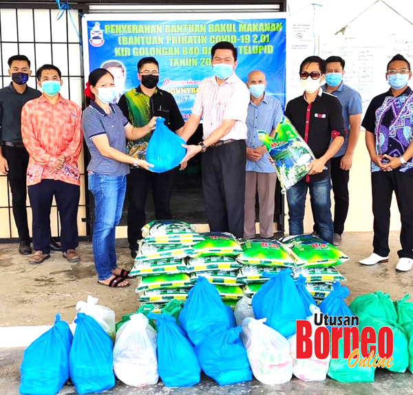  Jonnybone (tengah) menyerahkan bantuan bakul makanan kepada penduduk di Dewan Serbaguna Daerah Telupid.