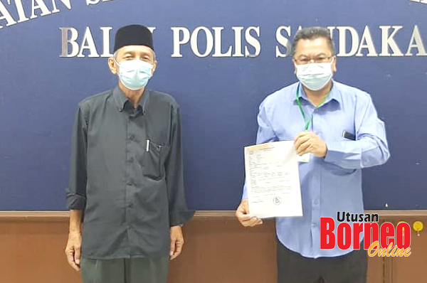  Zantapha (kanan) menunjukkan kertas laporan polis yang dibuat di Balai Polis Sandakan.