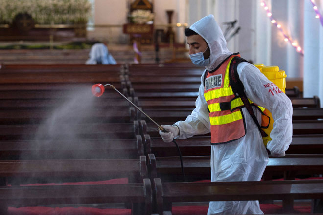  Seorang pekerja kesihatan melakukan kerja sanitasi di sebuah gereja di Peshawar. — Gambar AFP