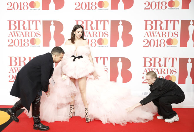  Gambar fail bertarikh 21 Februari 2018 menunjukkan penyanyi dan penulis lagu British Dua Lipa mendapat bantuan daripada  pekerja yang membetulkan gaunnya semasa tiba untuk Brit Awards 2018 di London. Artis wanita kembali mendominasi pencalonan Brit Awards 2021 yang telah diumumkan baru-baru ini, dengan empat orang wanita disenarai pendek bagi kategori album terbaik yang menjadi rebutan setiap tahun dalam acara tersebut.  — Gambar AFP