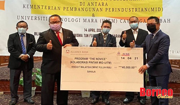  Abdul Kadir (kanan) menerima replika geran berjumlah RM40,000 sumbangan dari Kementerian Pembangunan Perindustrian yang disampaikan oleh Thomas (dua kiri) sambil disaksikan oleh Joachim (tengah).