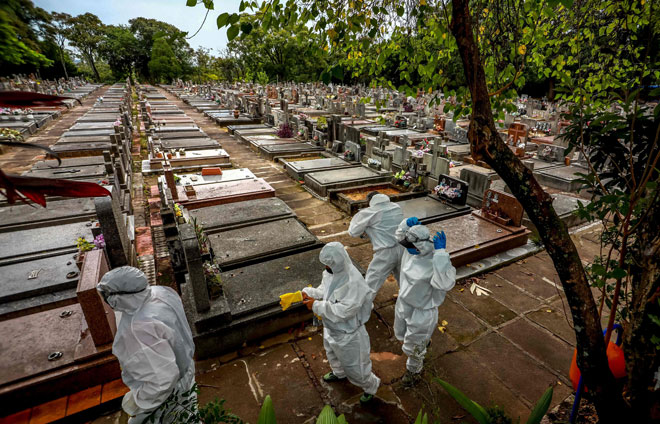  Gambar fail 26 Mac lalu menunjukkan para pekerja berseragam PPE bersiap sedia untuk mengebumikan mayat pesakit COVID-19 di perkuburan perbandaran Sao Joao di Porto Alegre. — Gambar AFP