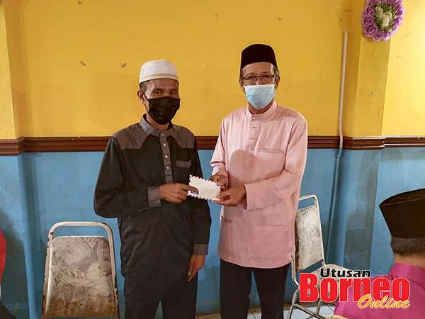  Kamarlin (kanan) menyampaikan sumbangan sempena bulan Ramadhan kepada salah seorang penerima dalam majlis berbuka puasa yang diadakan dekat Sipitang.