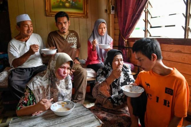 Azizah (dua, kanan) dibantu suami Kamaludin Embong, 70, menyuapkan sarapan pagi kepada anak-anaknya Orang Kurang Upaya (OKU) ketika ditemui di Kampung Keliyu. - Gambar Bernama.