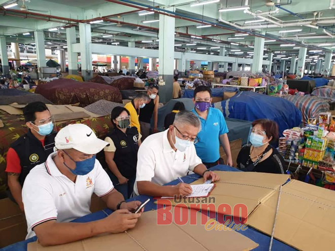  Ting (dua kiri, baju putih) membantu peniaga di Pasar Sentral Sibu pendaftaran program imunisasi COVID-19.