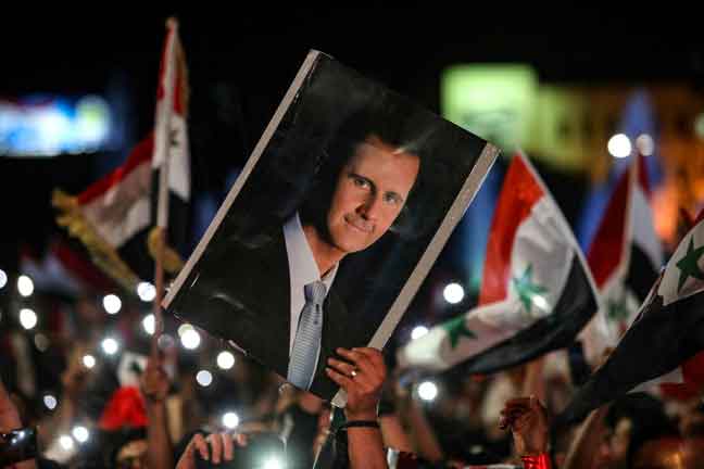 Penyokong membawa gambar potret Presiden Syria yang baharu, Bashar al-Assad selepas beliau memenangi pilihan raya di Syria. — Gambar AFP