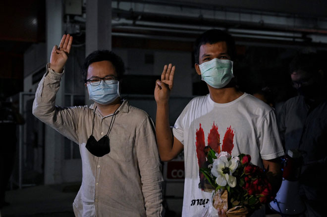  Anon Numpa (kiri) dan Panupong Jadnok menunjukkan tiga jari ketika meninggalkan Hospital Universiti Thammasat, selepas kedua-dua ketua protes prodemokrasi itu dibebaskan dengan ikat jamin ekoran dijangkiti COVID-19 ketika dalam penahanan praperbicaraan di Penjara Reman Bangkok kelmarin. — Gambar AFP