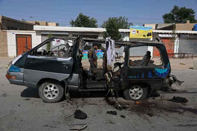 Anggota keselamatan dilihat berdiri berhampiran kenderaan yang musnah dalam letupan bom di Kabul, Afghanistan kelmarin. — Gambar AFP