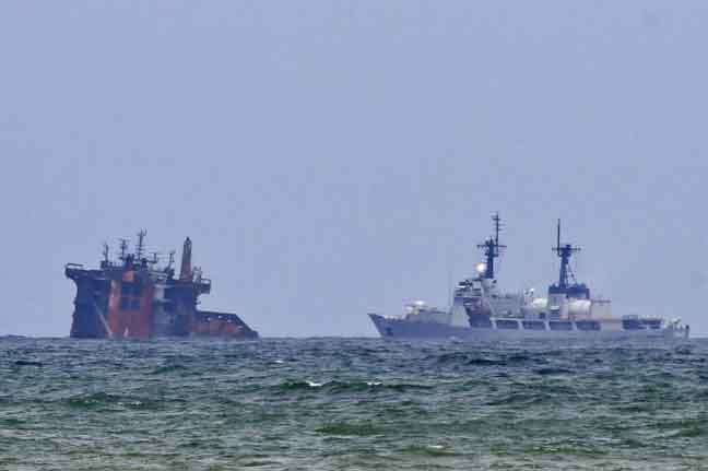  Sebuah kapal (kanan) kelihatan menghampiri kapal MV X-Press Pearl yang separuh karam selepas dijilat api selama hampir dua minggu di luar pelabuhan Colombo, Sri Lanka semalam. — Gambar AFP